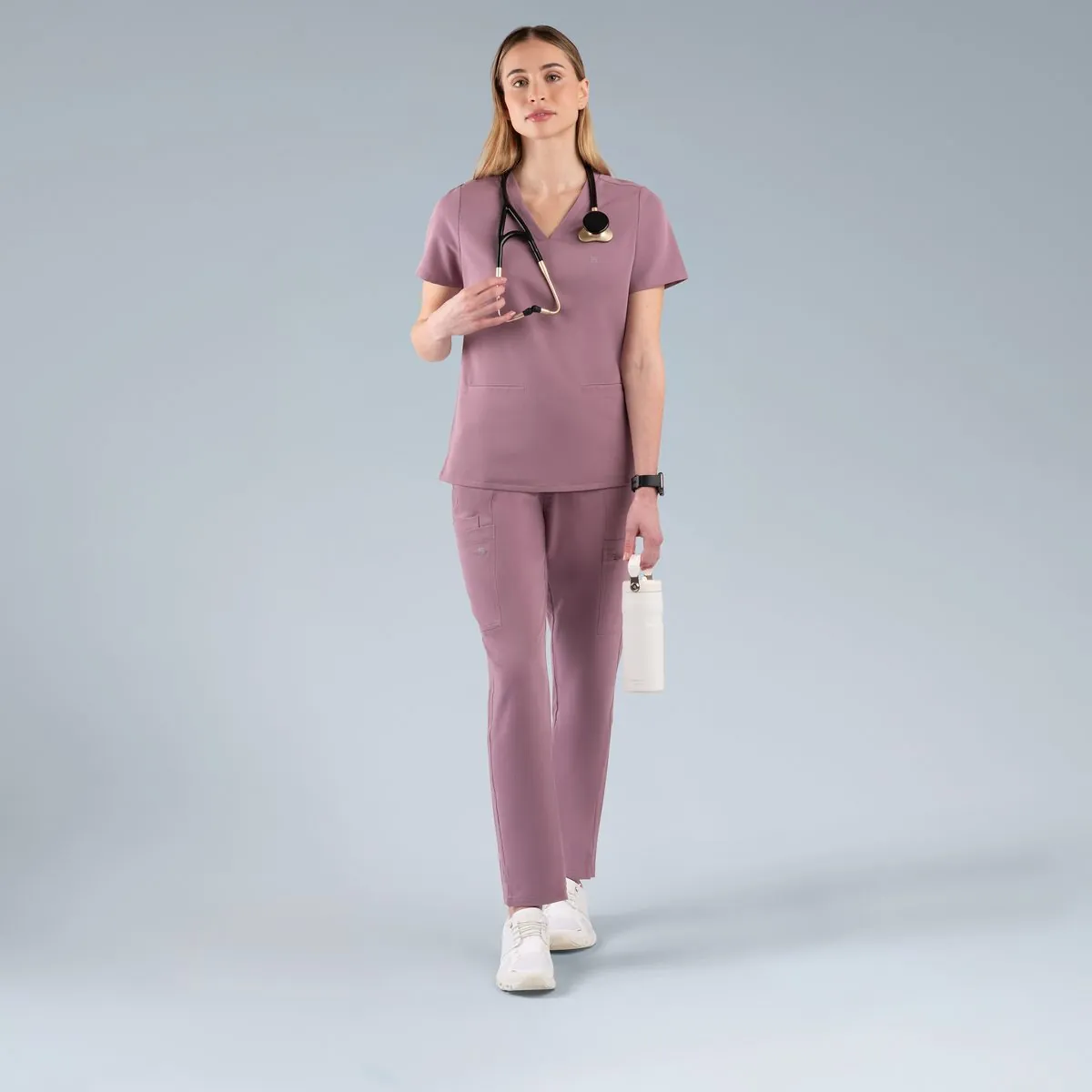 Model in mauve scrubs on a grey studio backdrop