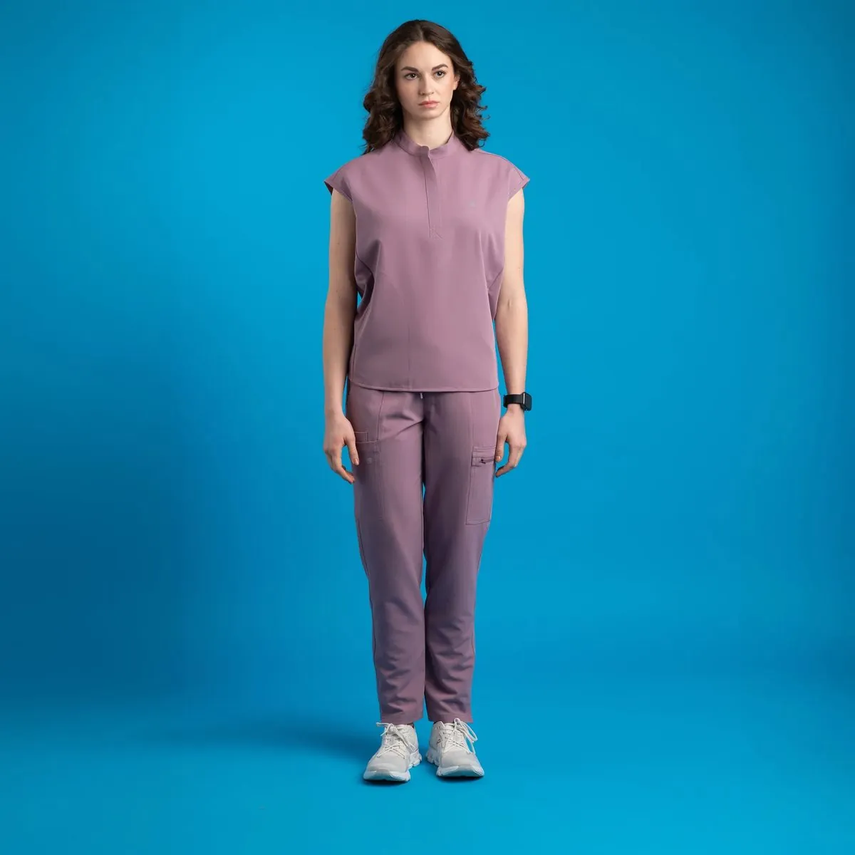 Model in mauve scrubs on a blue backdrop