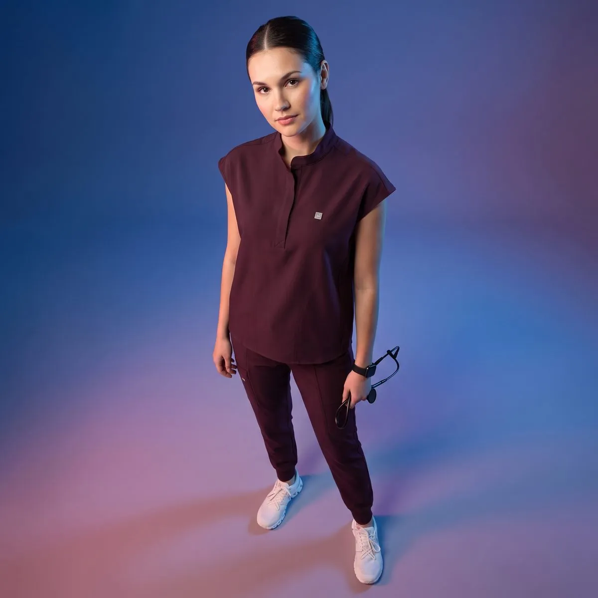 Model in maroon scrubs on a gradient backdrop