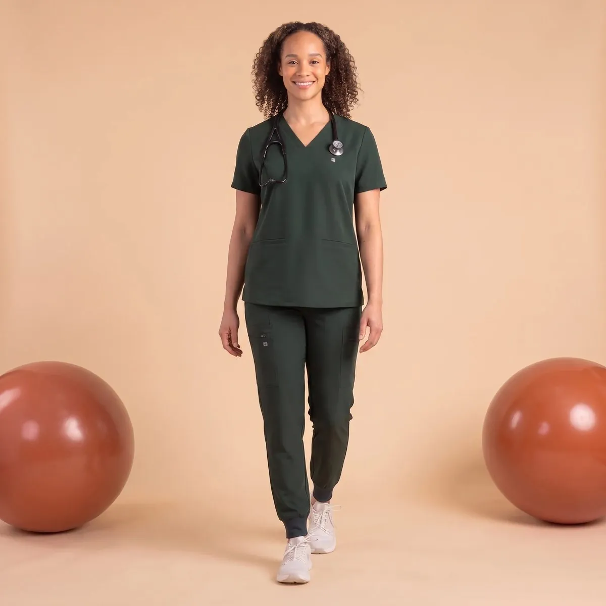 Model in forest green scrubs on a warm set