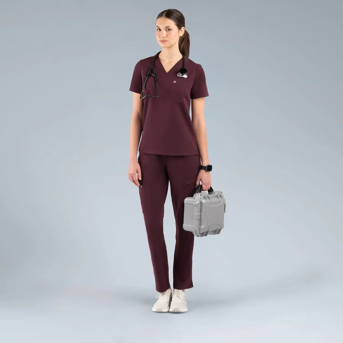 Model in burgundy scrubs holding a lunch bag