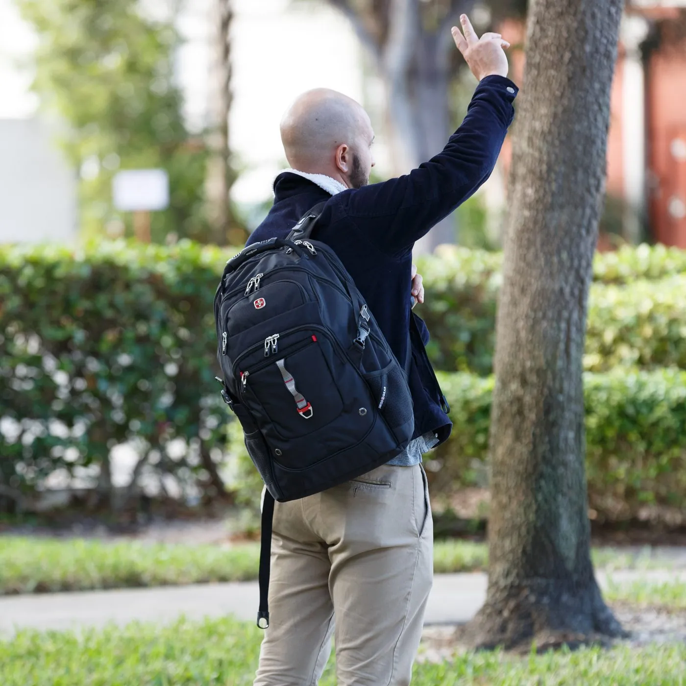 Man with a SwissGear backpack on a leafy street