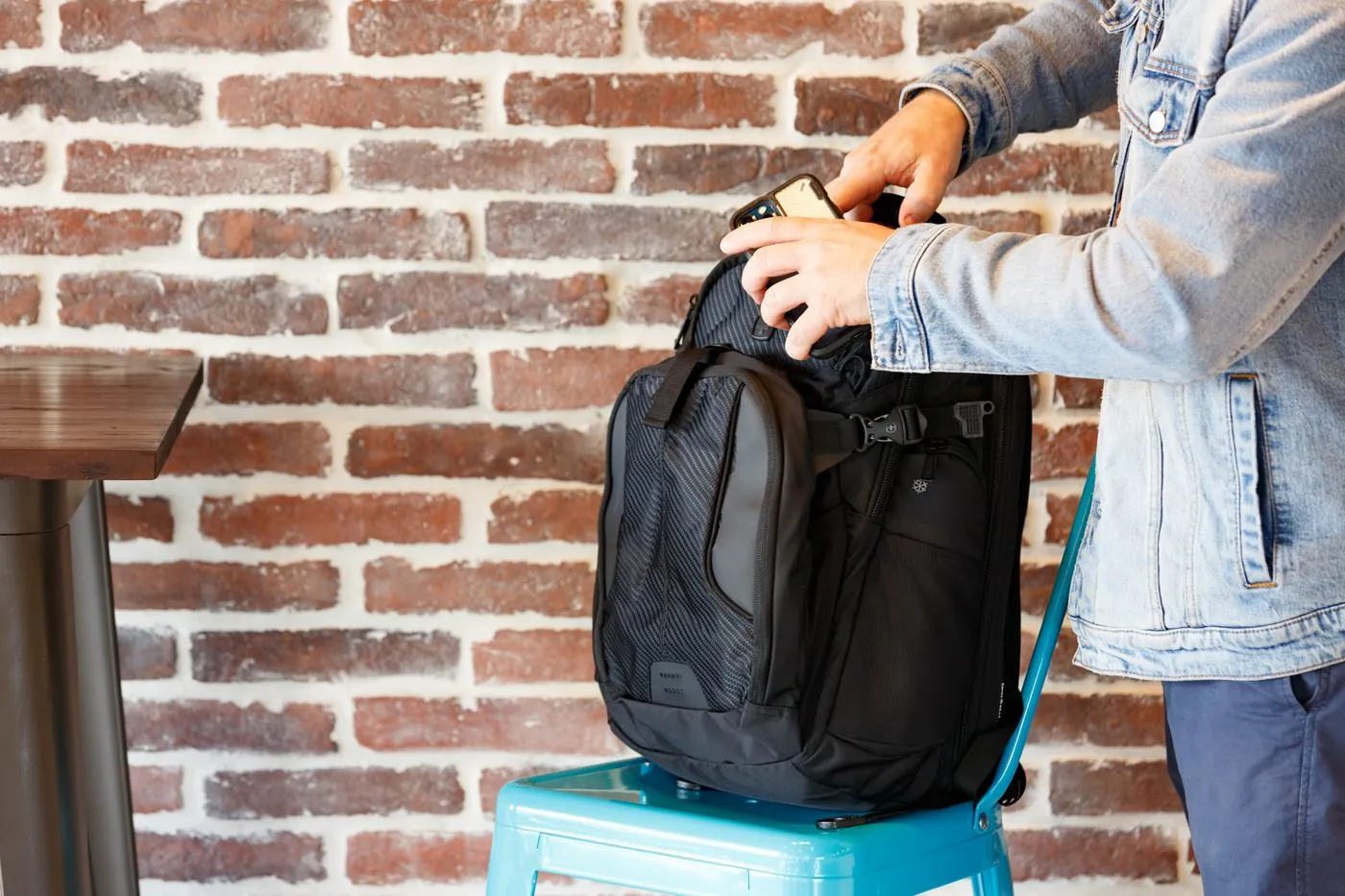 Two people with SwissGear backpacks by a brick wall