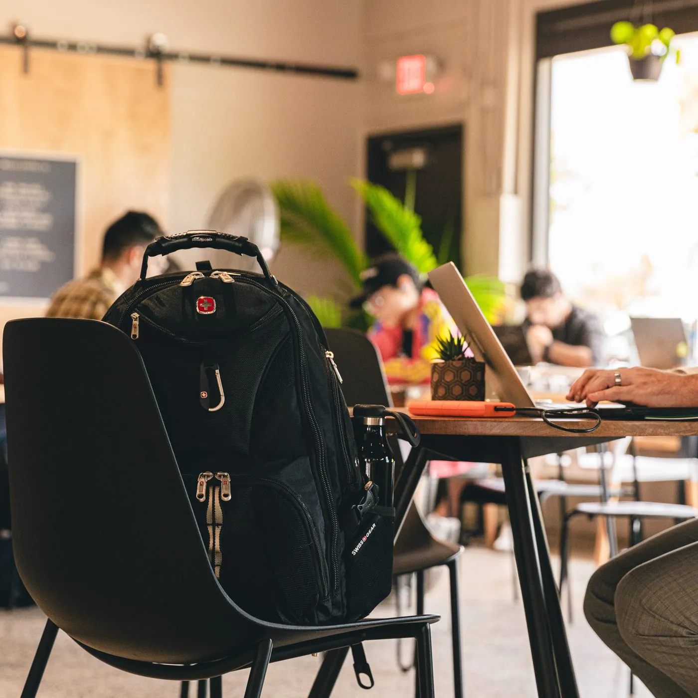 SwissGear backpack on a chair in a busy coffee shop