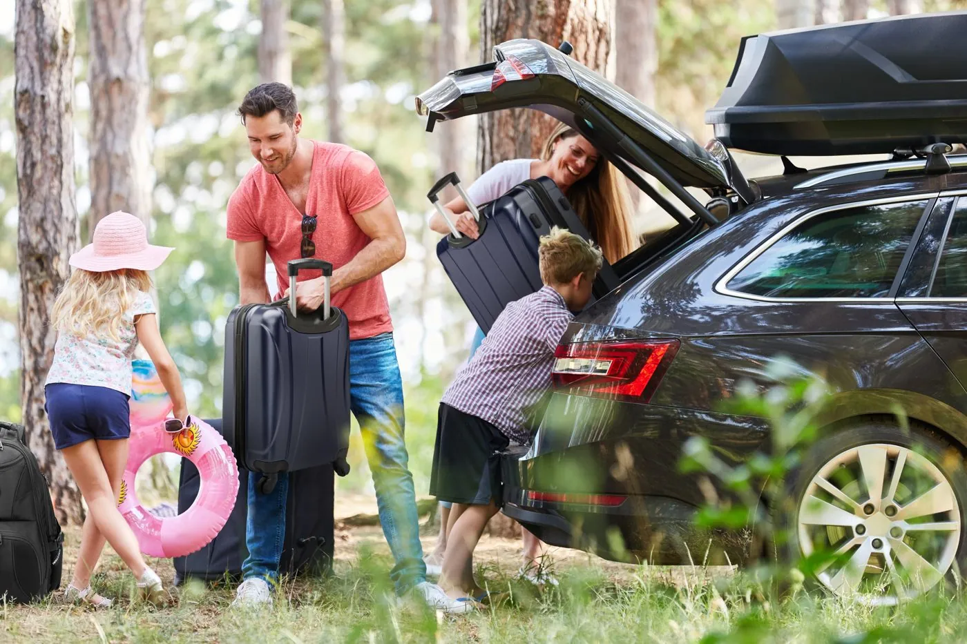 Family loading SwissGear luggage into a car for a road trip