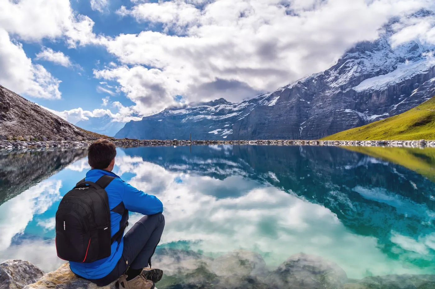 Traveller with a SwissGear backpack sitting by a mountain lake