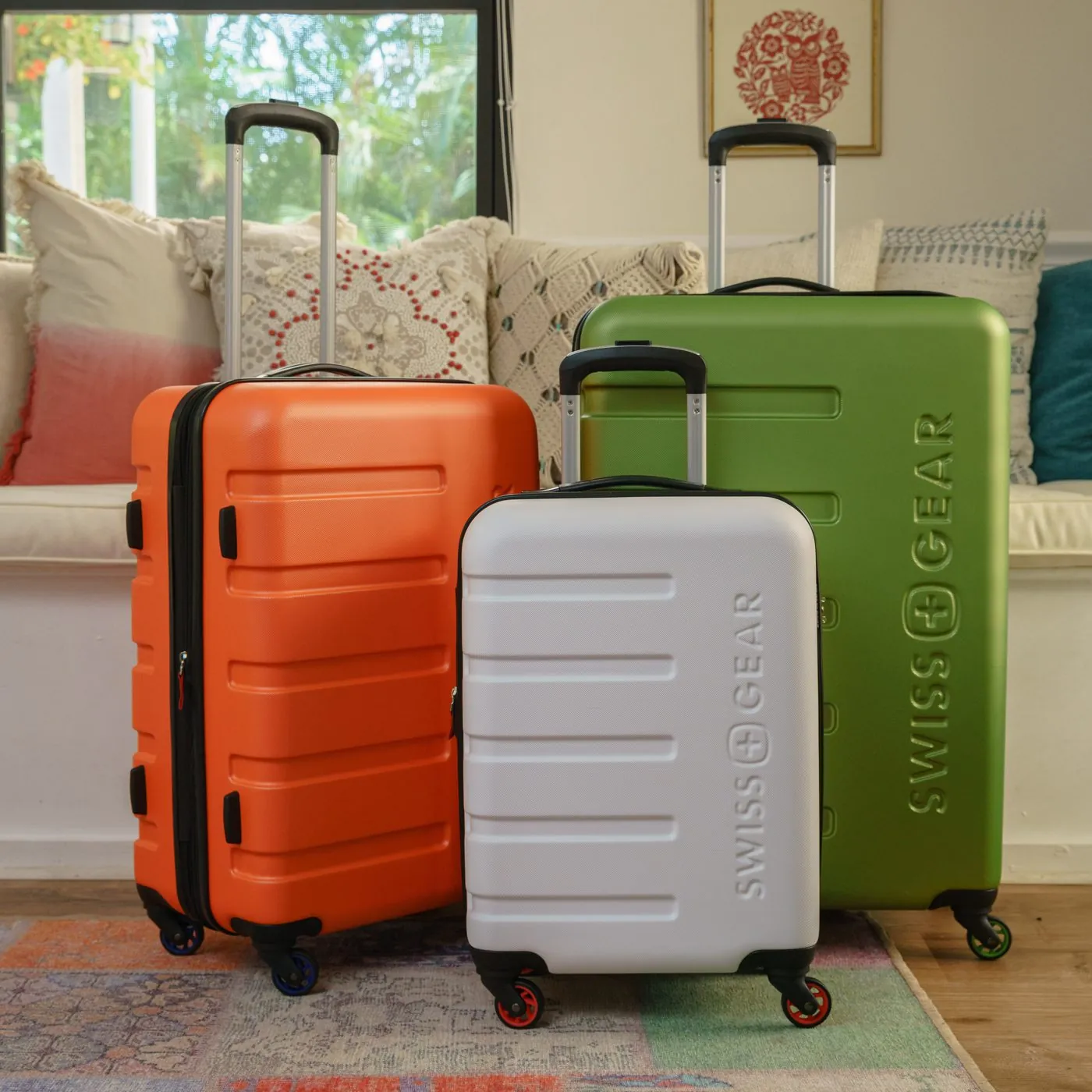Orange, white and green SwissGear luggage in a sunny living room
