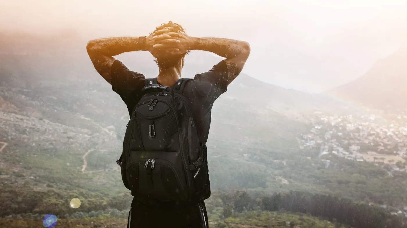 Hiker with a SwissGear backpack looking over a misty valley