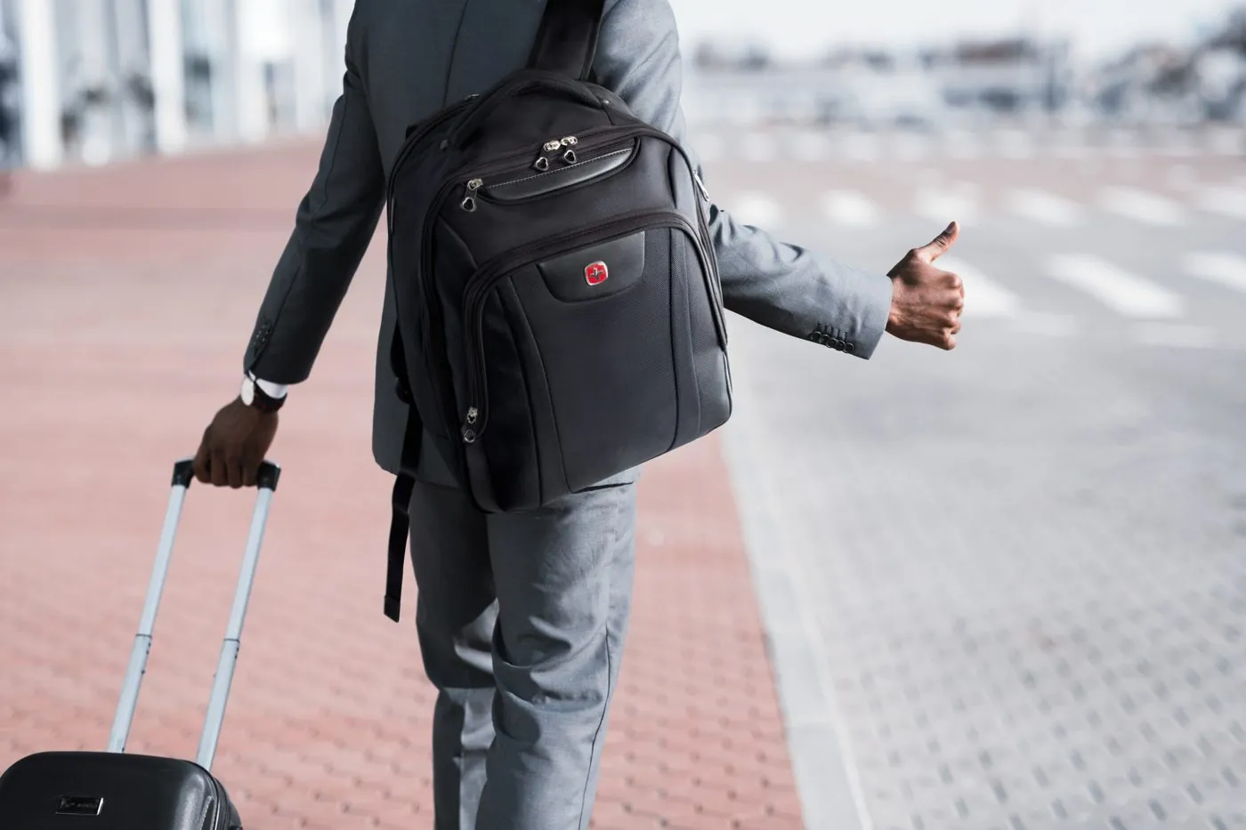Traveller with a SwissGear backpack and roller hailing a ride
