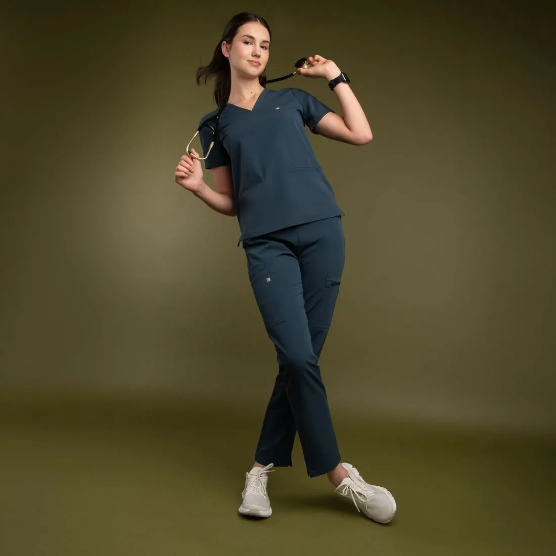 Model in a slate scrub set turning against an olive backdrop