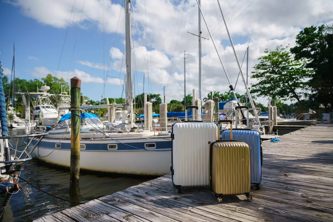 SwissGear hardside luggage set on a wooden dock beside sailboats