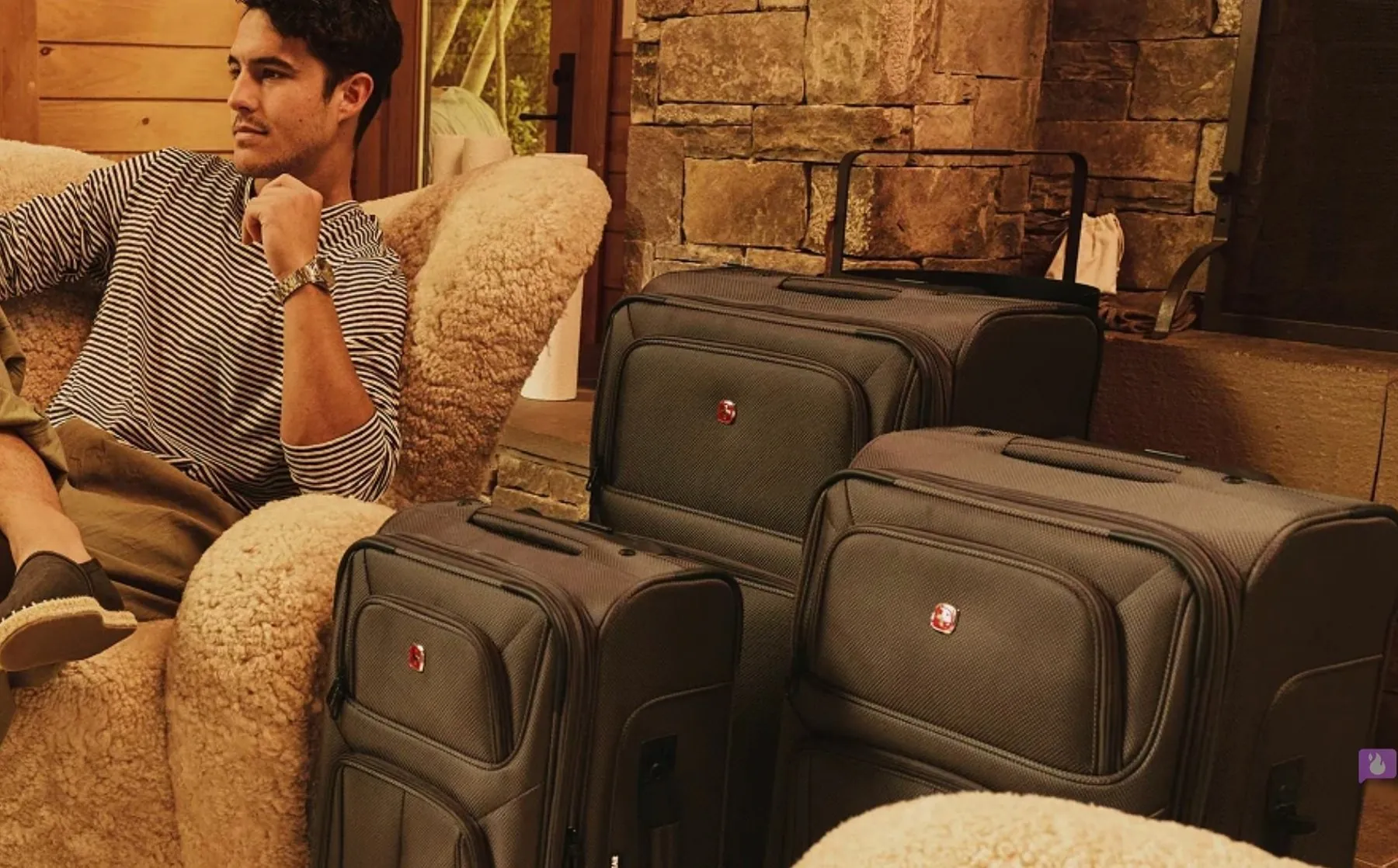 Man relaxing in a sheepskin chair beside SwissGear luggage